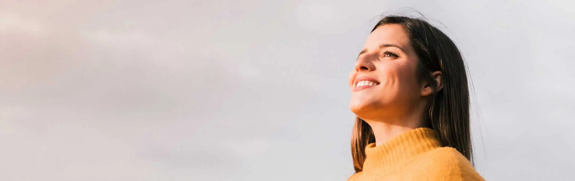 Mujer joven mirando al horizonte con confianza, simbolizando optimismo y éxito financiero en inversiones.