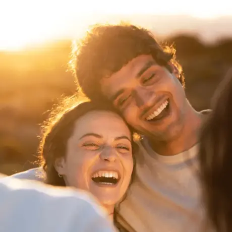 Amigos riendo al atardecer, celebrando metas alcanzadas con buenas decisiones financieras.